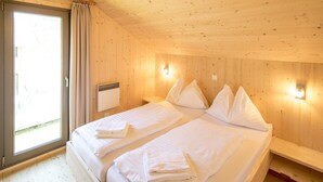 A wooden cabin room with two beds, a window, and wall-mounted lights. - Lovely chalet with whirlpool (Murau)