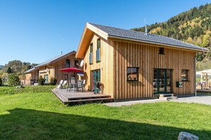 Una cabaña de madera con terraza, mobiliario exterior y zona de barbacoa.