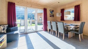 A wooden interior with a dining area, sliding glass doors to a patio, and a painting on the wall.