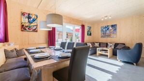 A modern interior with a wooden dining table set for four, a sofa, and a blue armchair.