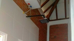 Un baño con ducha, inodoro y un pequeño ventanal.