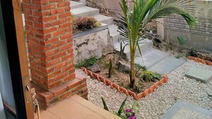 Un pilar de ladrillo, una palmera y un camino de hormigón en un jardín.