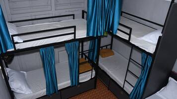 Een studentenkamer met stapelbedden, blauwe gordijnen en een kamer met een patroon op de vloer.