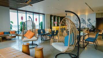A modern lounge area with wicker chairs, sofas, and a dining area.