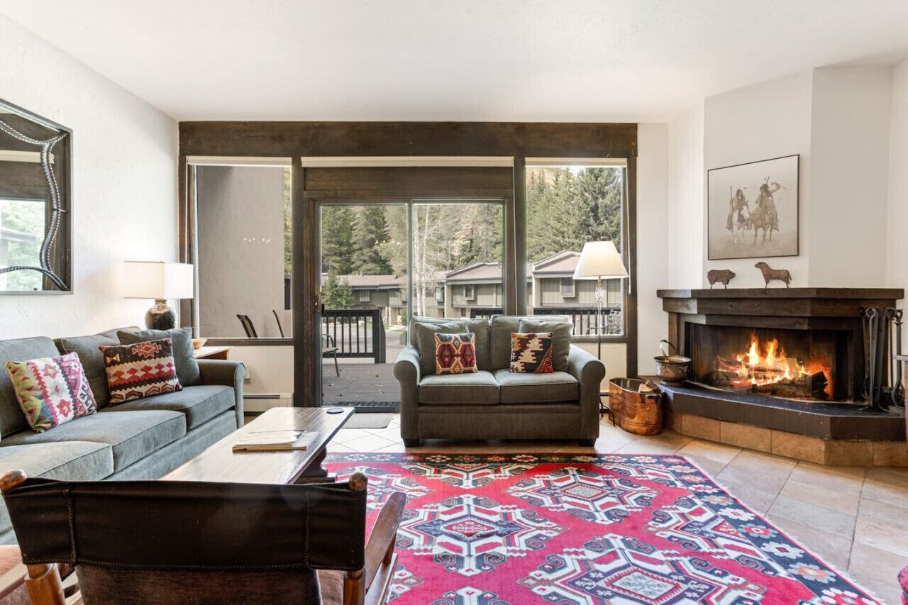 A living room with a fireplace, a sofa, a coffee table, and a patterned rug.