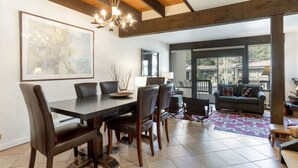 Un espace repas comprenant une grande table et des chaises, un lustre et une grande carte encadrée accrochée au mur.