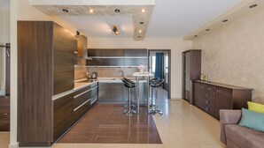 A modern kitchen with dark wood cabinetry, stainless steel appliances, and a central island with stools. - Apartamenty Sun & Snow Villa Nord (Wladyslawowo)