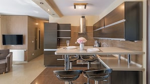 A modern kitchen with a central island, stainless steel appliances, and a flat-screen TV mounted on the wall. - Apartamenty Sun & Snow Villa Nord (Wladyslawowo)