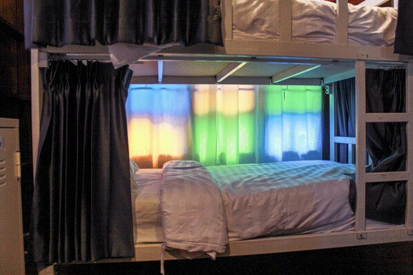 A bunk bed with a window, curtains, and a bed with a checkered blanket. - Agga CNX Hostel (Chiang Mai)