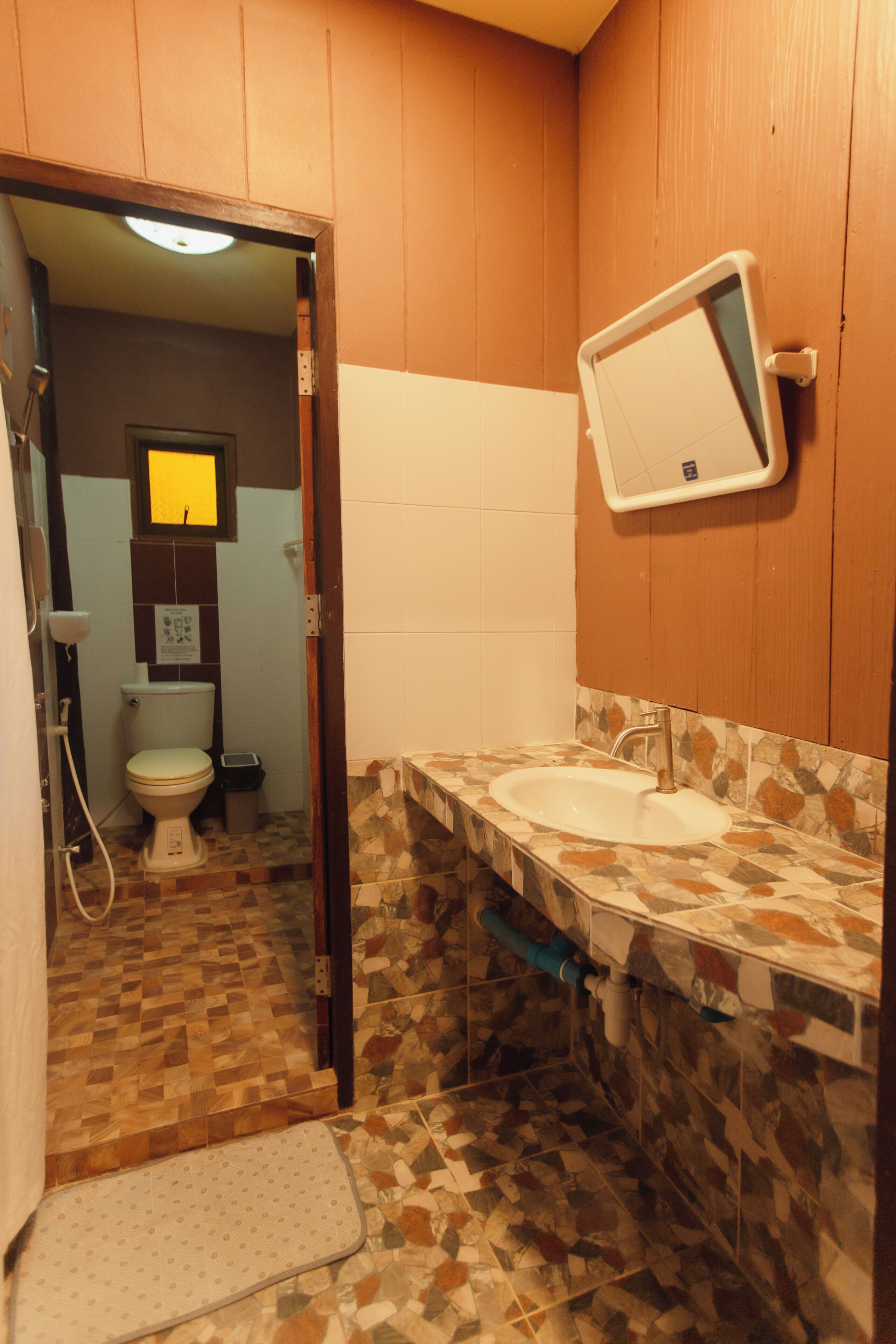 Een badkamer met betegelde vloer, een wastafel, een spiegel en een toilet.