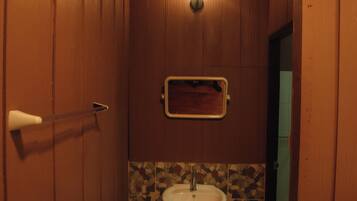 A small bathroom with a wooden door, a white sink, and a mosaic tile backsplash.