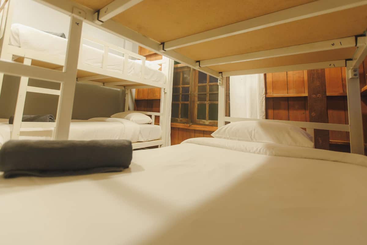 A bunk bed room with white bedding and a wooden headboard.