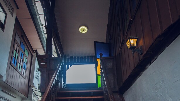 A wooden staircase with a handrail leading to a landing. - Agga CNX Hostel (Chiang Mai)