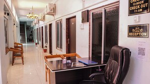 Un espace d’accueil comprenant un comptoir, un fauteuil en cuir noir, une chaise en bois et un panneau d’identification pour la réception.