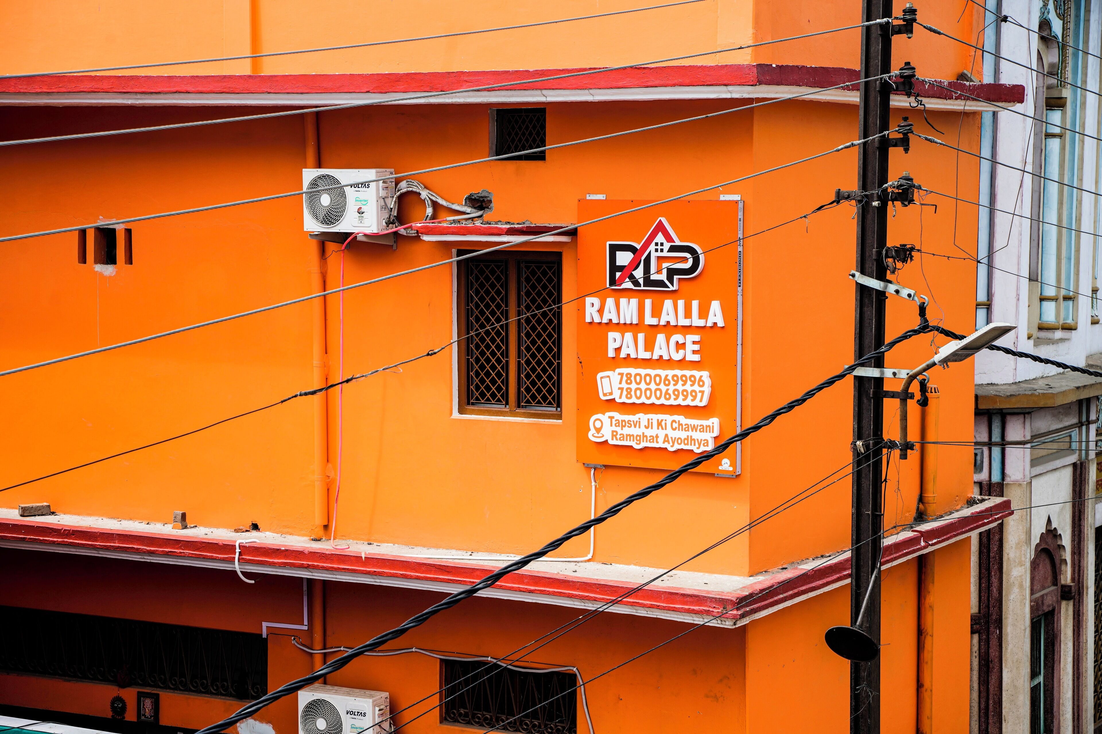 Een gebouw met een bord waarop Ram Lalla Palace staat, inclusief een telefoonnummer en locatiegegevens.