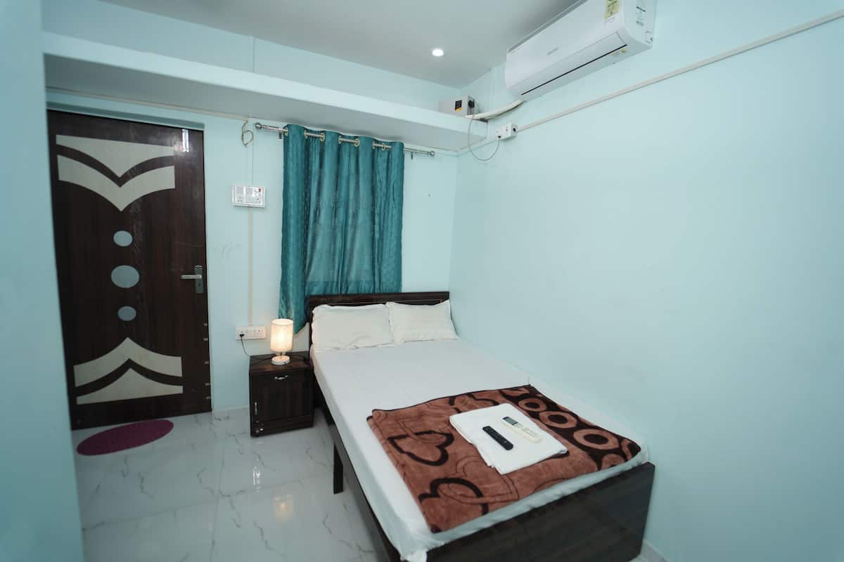 A bedroom with a bed, a nightstand, a wall-mounted air conditioner, and a door with a decorative design.