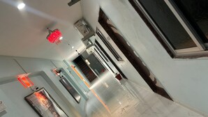 Un couloir doté d’un sol en marbre, d’un luminaire rouge suspendu et d’un tableau encadré accroché au mur.