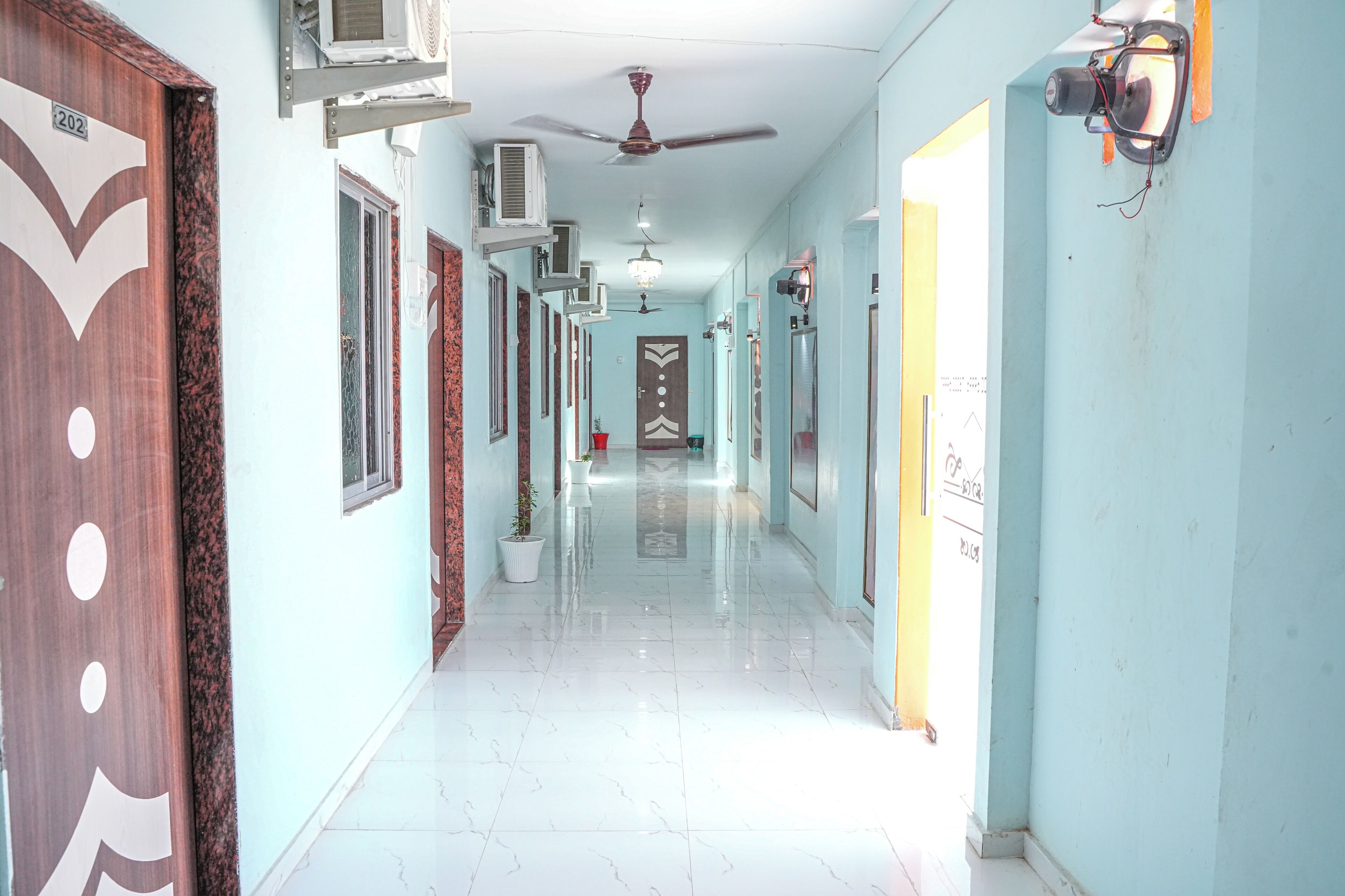 A corridor with a ceiling fan, air conditioning units, and a chandelier.