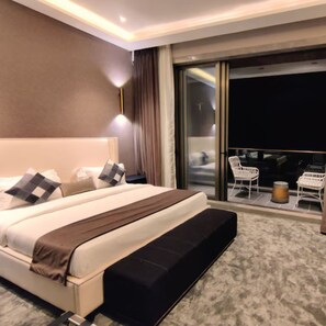 Ein modernes Hotelzimmer mit einem großen Bett, einer kleinen Sitzecke mit Stühlen und einem Balkon mit Blick.