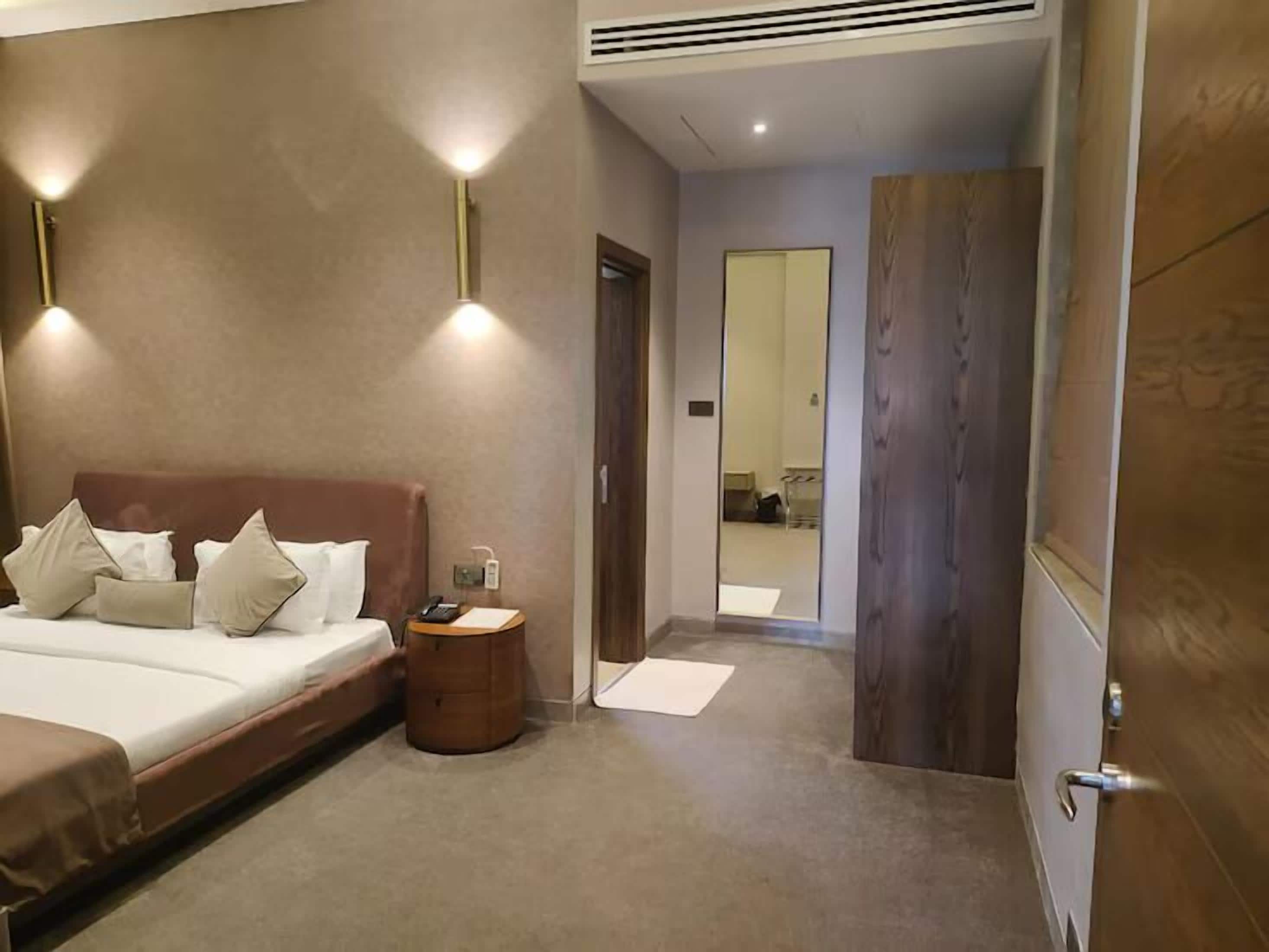 Quarto de hotel com cama, mesa de cabeceira e espelho.