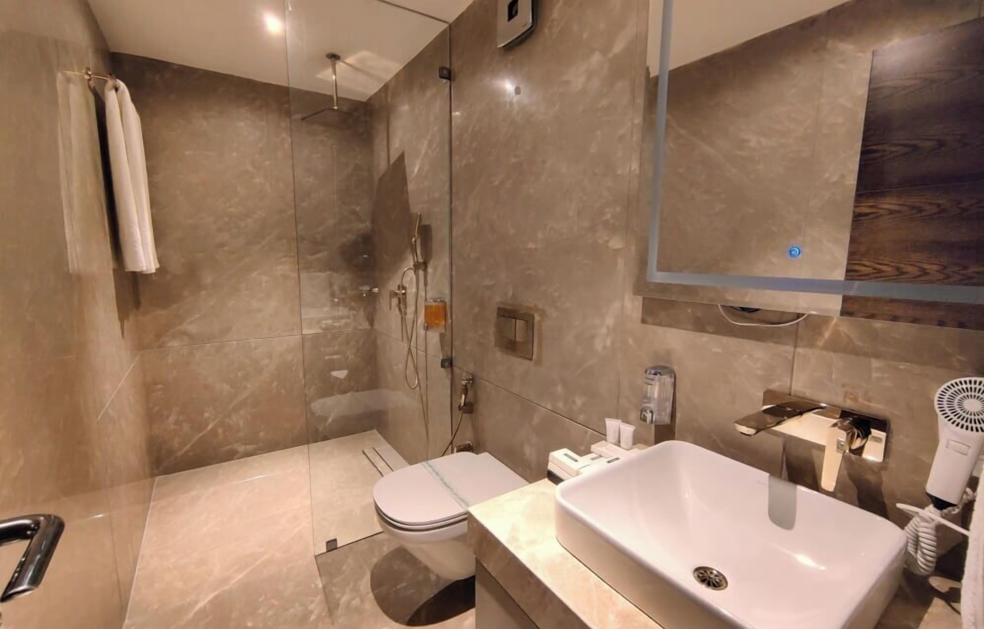 A modern bathroom with a glass-enclosed shower, a white sink, and a large mirror.