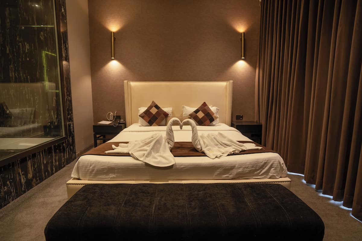 A hotel room with a large bed, two bedside tables, a mirror, and a curtain.