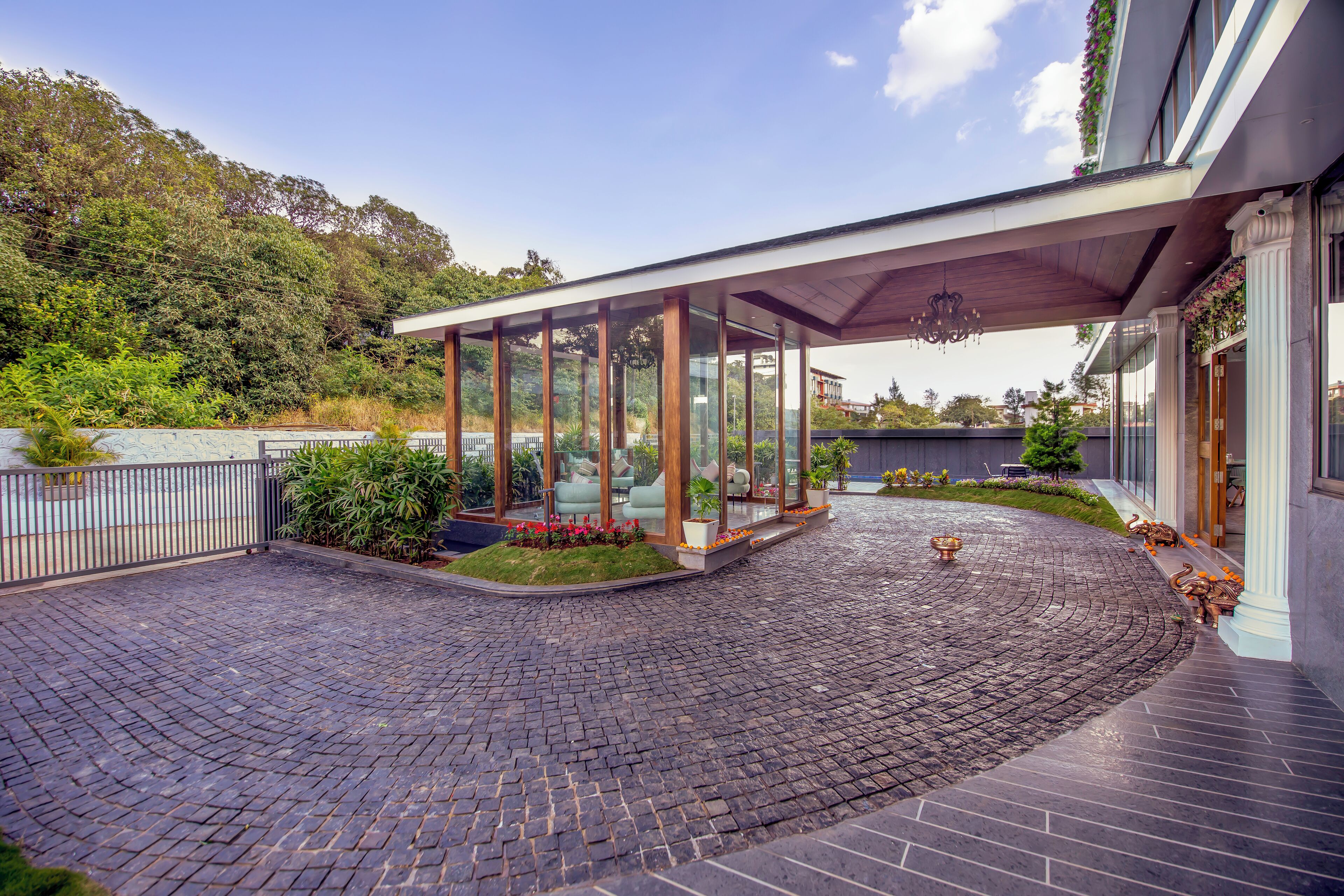 A modern building with a covered outdoor area, a paved courtyard, and a view of a hillside.