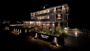 Un hotel su due piani con un balcone al secondo piano, una zona esterna coperta e un cartello che riporta la scritta "Leola Resort".