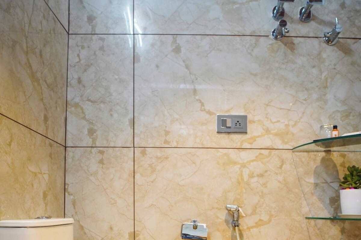 A bathroom with a toilet, a shower, and a glass shelf.