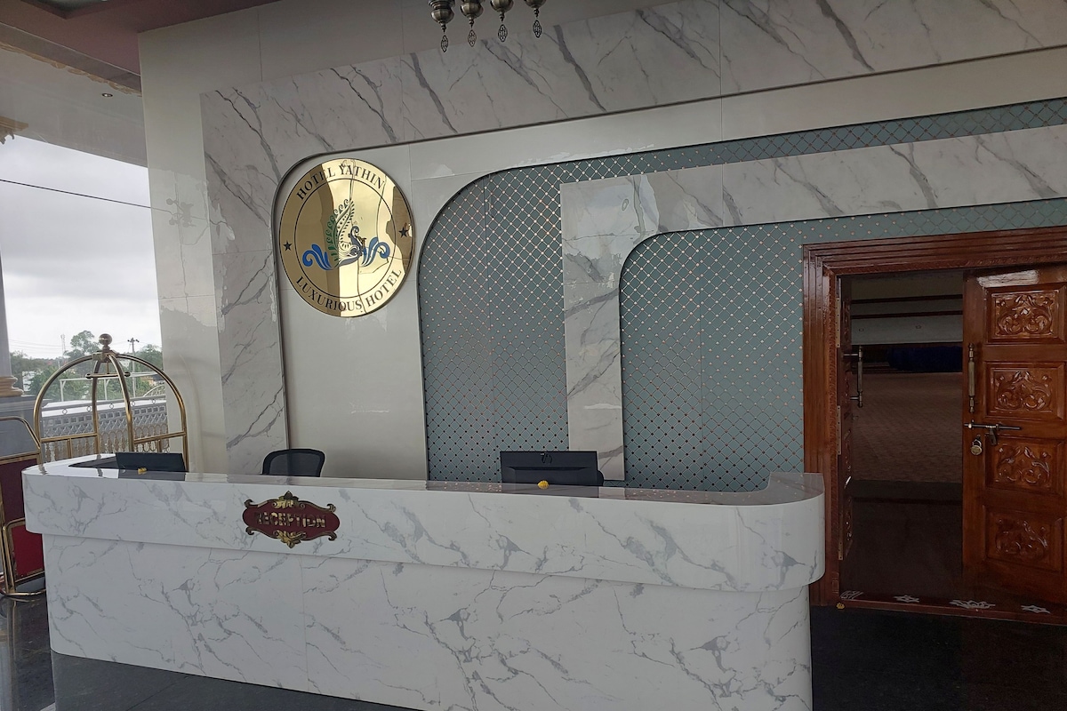 A reception desk with a marble top, a logo above it, and a patterned wall behind.