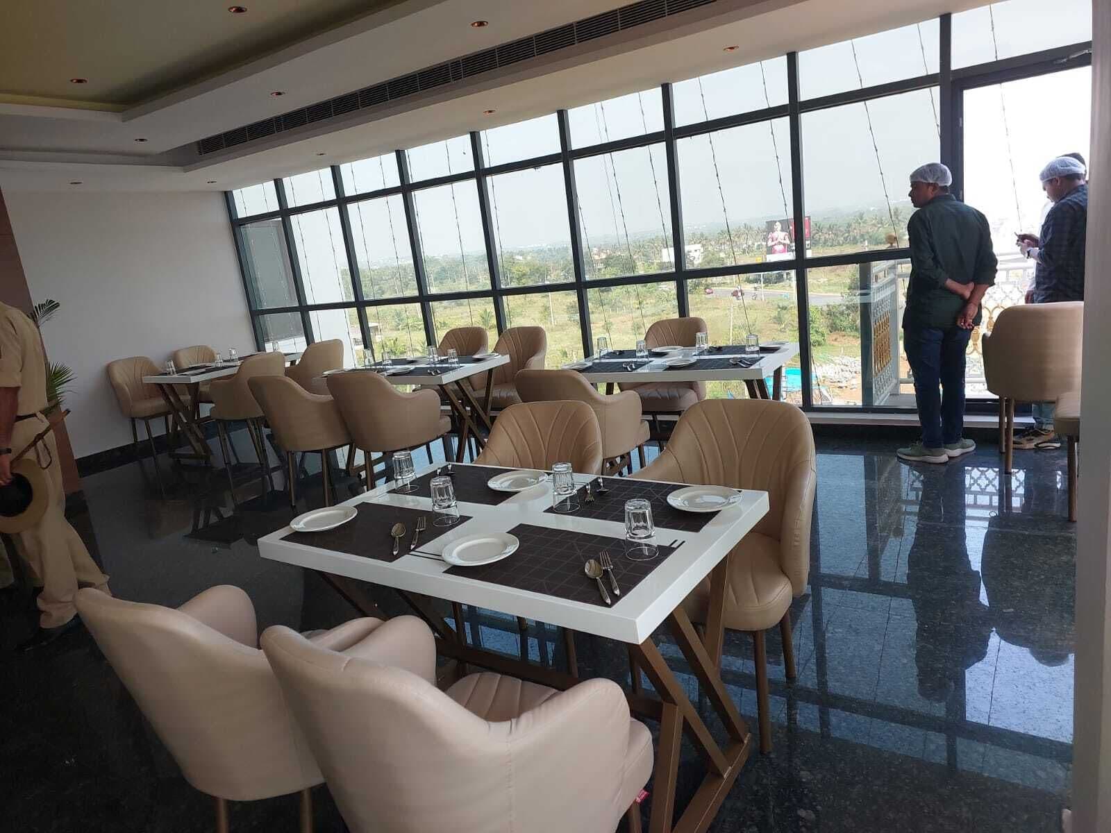 Un espace repas avec des tables disposées pour accueillir quatre personnes, de grandes fenêtres offrant une vue sur l’extérieur et un aménagement intérieur propre et moderne.