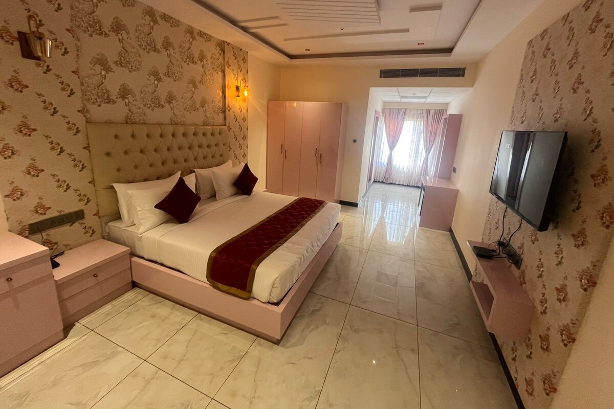A bedroom with a large bed, a TV, and a wardrobe.