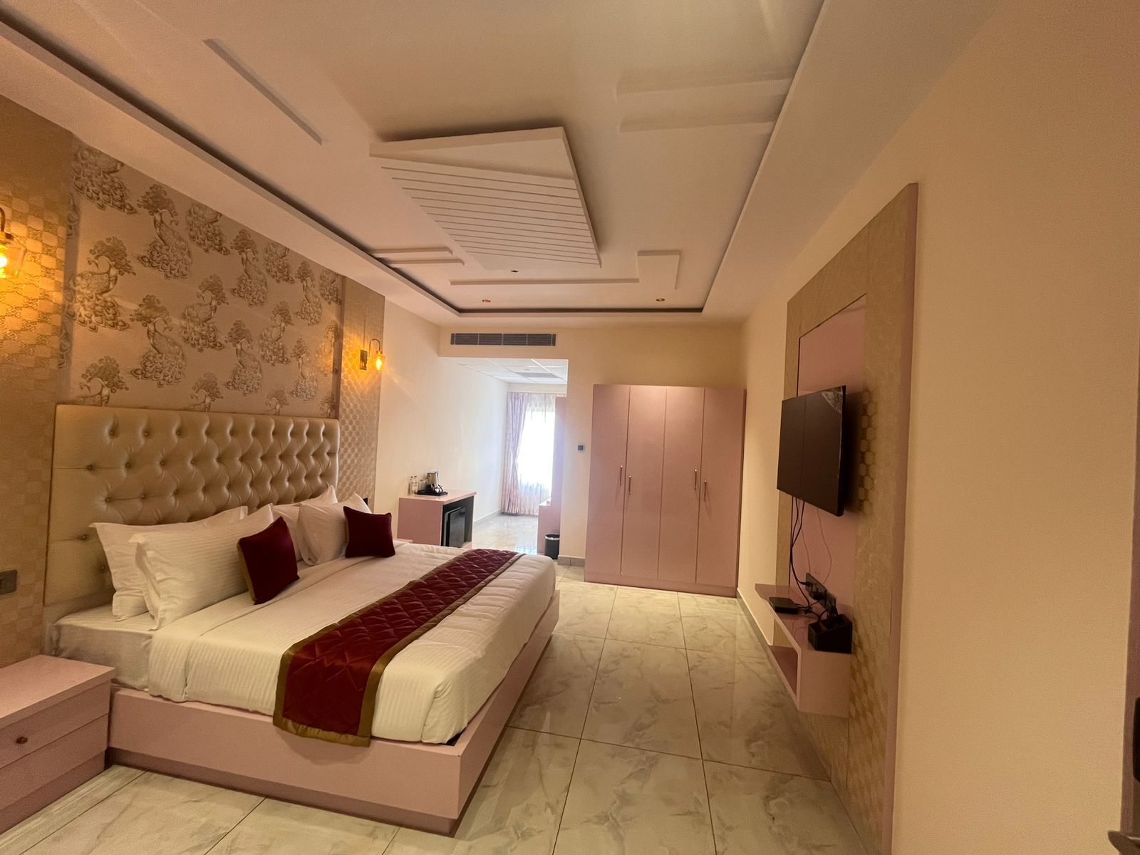 A modern bedroom with a large bed, a TV mounted on the wall, and a wardrobe.