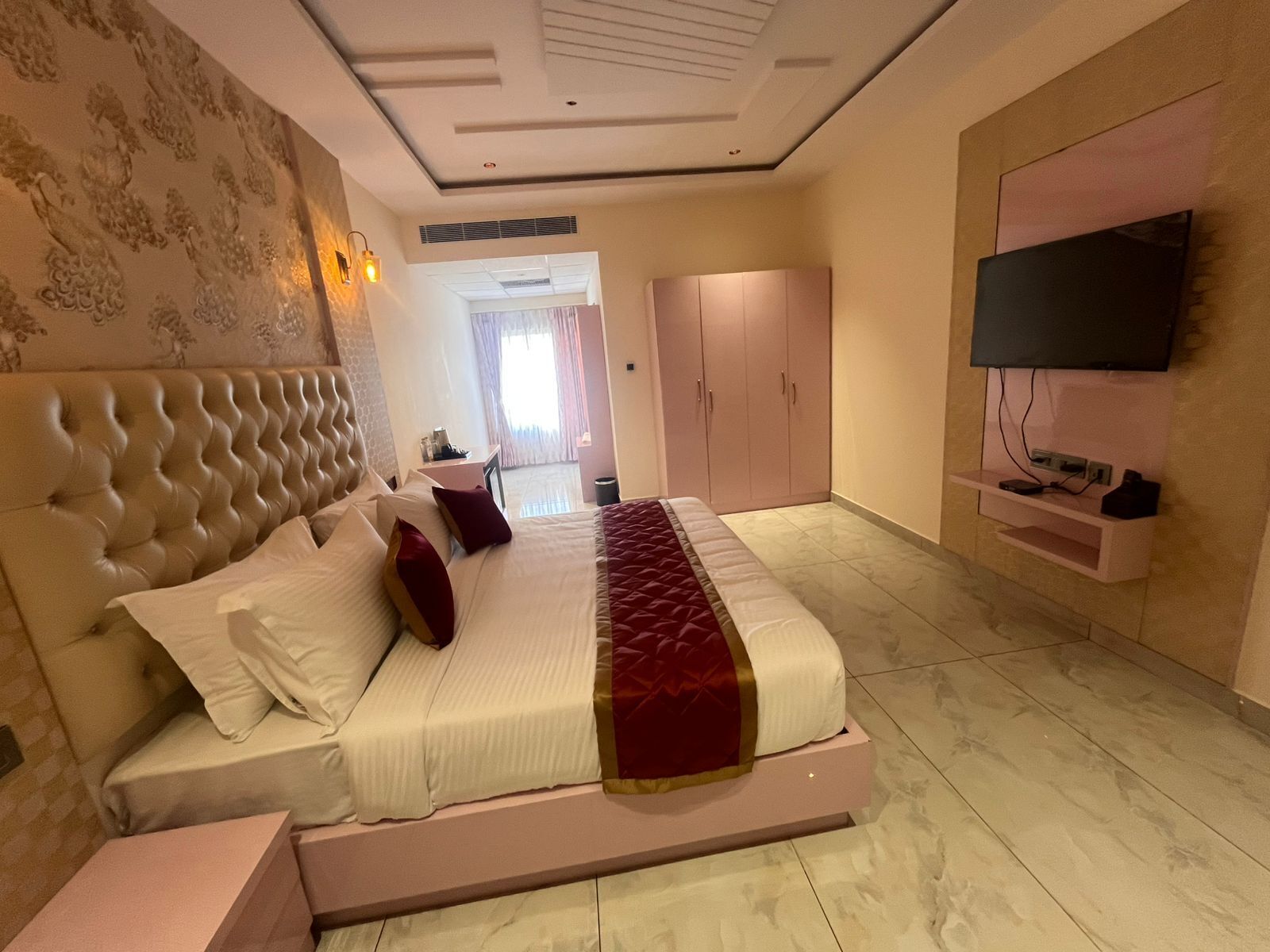 Un dormitorio con una cama grande, un televisor en la pared y un armario.