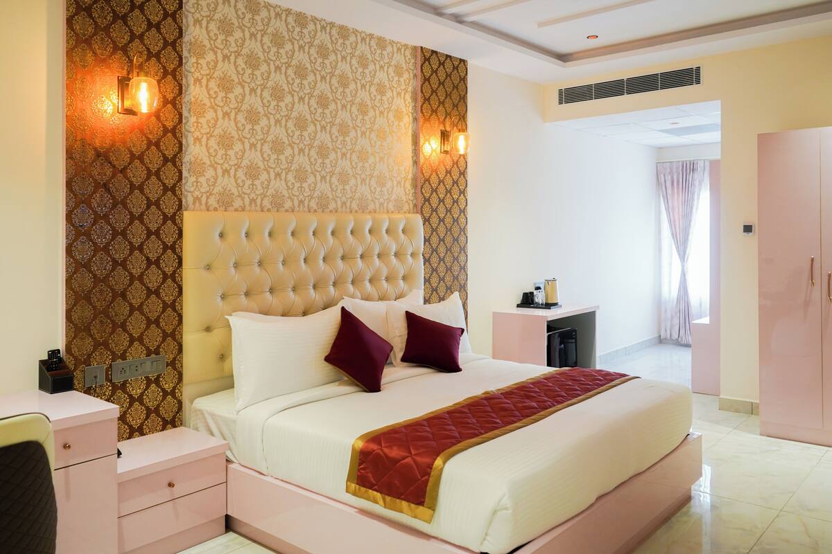 A well-appointed bedroom with a tufted headboard, a bedside table, a nightstand, and a wardrobe.