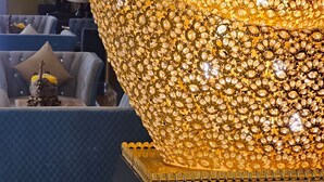 Un lobby lujoso con una gran pieza decorativa dorada, muebles modernos y un revestimiento de panel de madera.
