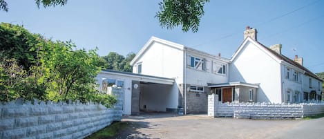 A two-story house with a garage, surrounded by a white fence and greenery.