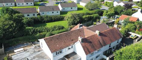 A residential area with multiple houses, a central white building with a red roof, and surrounding greenery.