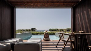 A wooden deck with lounge chairs and a table, overlooking a swimming pool and a scenic landscape.