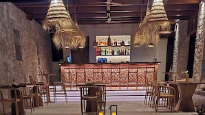 A bar area with wooden furniture and hanging lights.