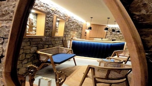 A mirror reflecting a room with stone walls, a blue sofa, wicker chairs, and a wooden table.