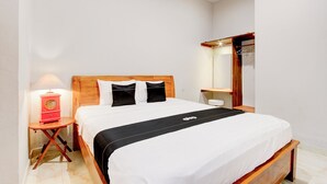 A neatly made bed with a black and white bedspread, a wooden headboard, and a small bedside table with a lamp. - Capital O 94274 Homestay Balimoelih  (Yogyakarta)