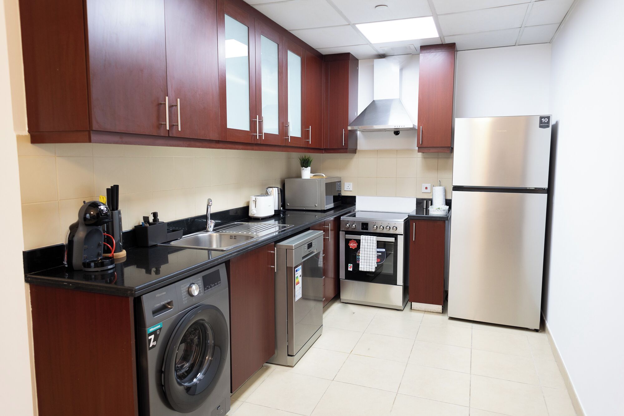 Une cuisine compacte équipée d’un lave-linge, d’un four à micro-ondes, d’un grille-pain, d’une cuisinière et d’un réfrigérateur.