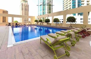 A rooftop pool with lounge chairs and a view of surrounding high-rise buildings. - HAPPY SEASON I Royal Oceanic apartment  (Dubai)