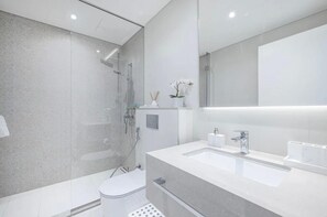 A modern bathroom with a glass-enclosed shower, a large mirror, and a white sink. - HAPPY SEASON I La Vie apartment  (Dubai)