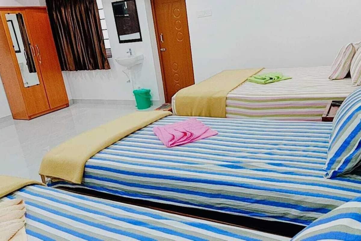 Habitación de hotel con dos camas, un armario, un lavabo y un espejo.
