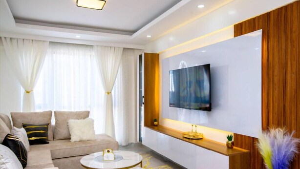 Un salon moderne avec un canapé, une table basse et un téléviseur fixé au mur.