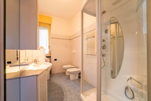 Une salle de bain moderne avec une douche à parois de verre, un meuble-lavabo à deux vasques et des toilettes.