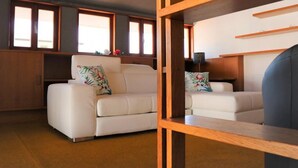 A modern living room with two white sofas, wooden shelves, and large windows. - Villa with garden and cosy attic (Cividale del Friuli)