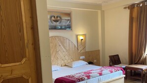 A hotel room with a wooden bed, a desk, a chair, and a painting of swans on the wall. - Shubham Cottage (Manali)